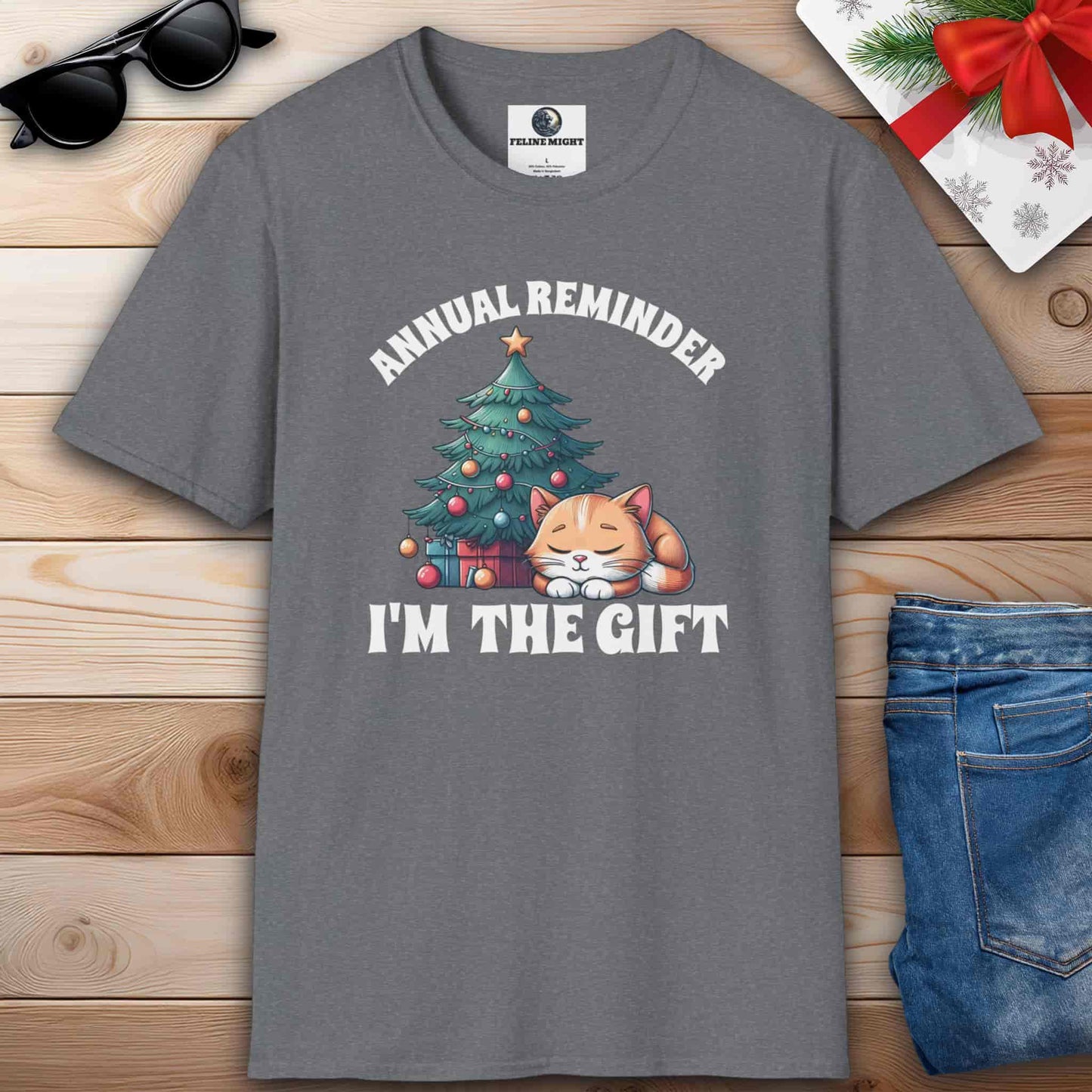 Athletic heather grey t-shirt with 'Annual Reminder, I'm the Gift' and a cute cat sleeping beside a Christmas tree.