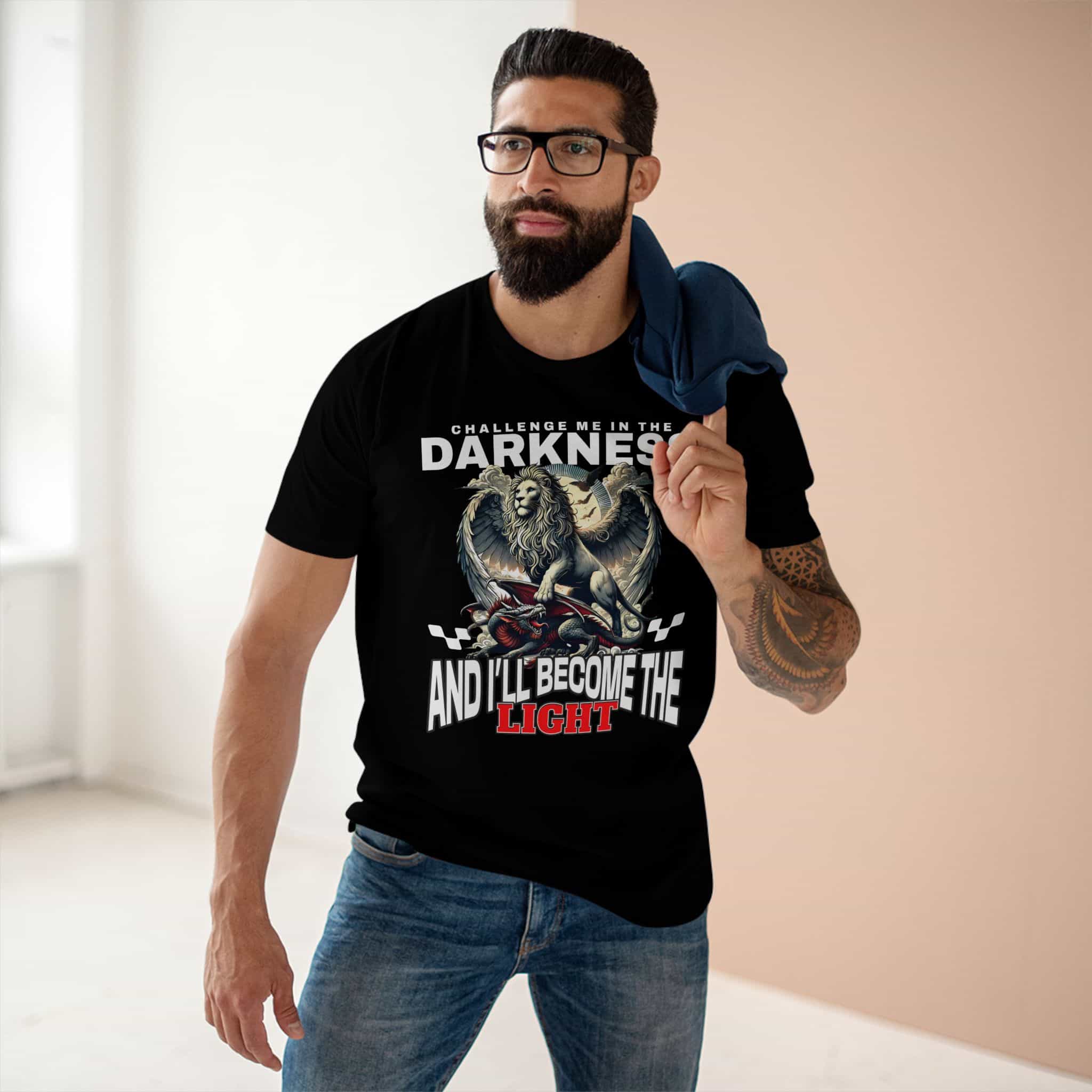 A man wearing a Black "Challenge Me" Lion T-Shirt featuring a majestic winged lion graphic and the text "Challenge me in the Darkness and I'll Become the Light".