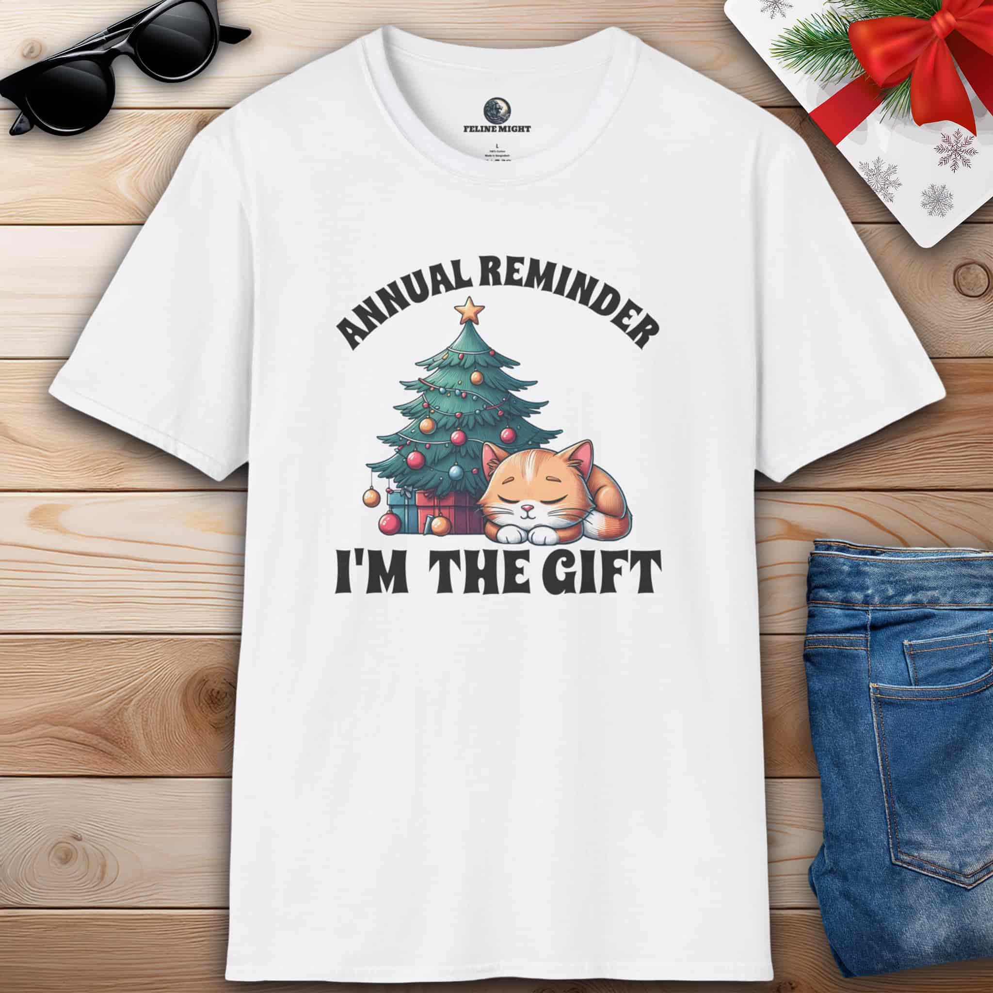 White t-shirt with 'Annual Reminder, I'm the Gift' and a cute cat sleeping beside a Christmas tree.