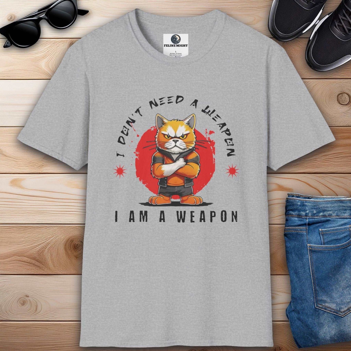 Grey t-shirt featuring a cartoon cat with the phrase 'I Don't Need A Weapon, I Am A Weapon'