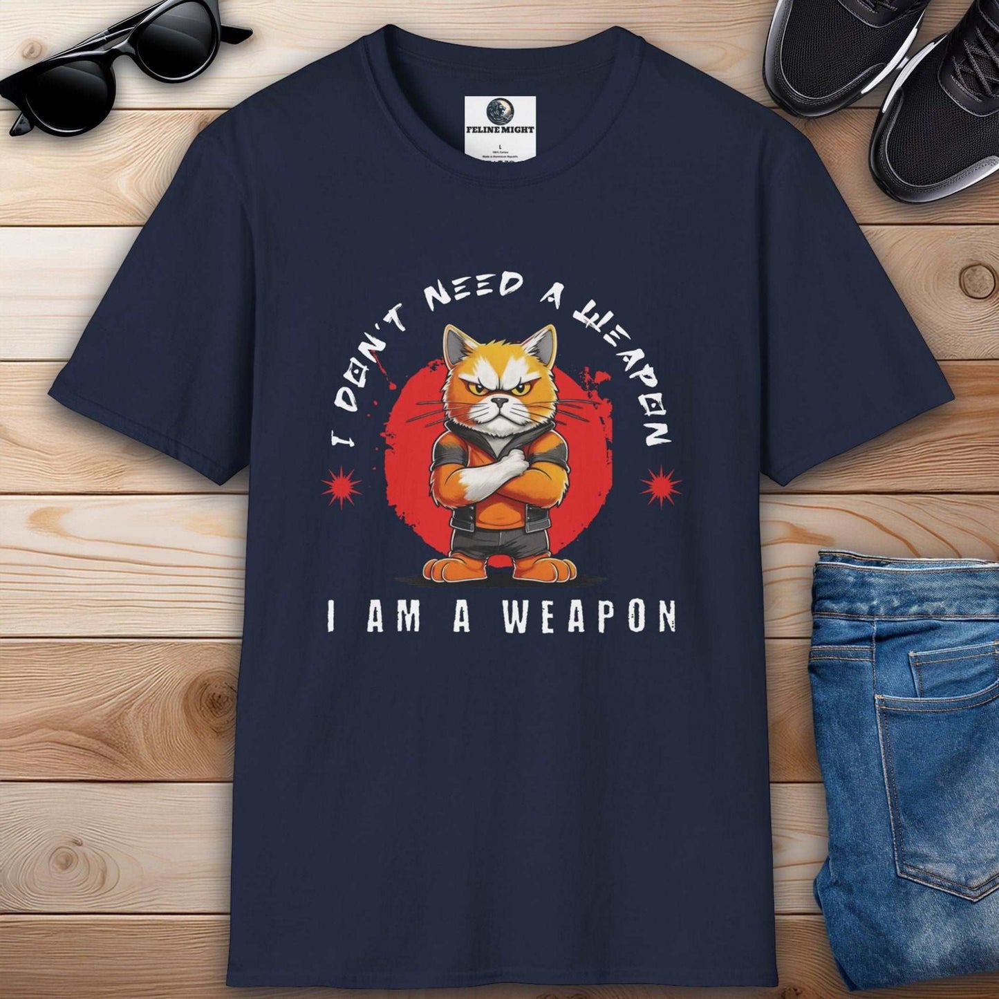 Navy blue t-shirt featuring a cartoon cat with the phrase 'I Don't Need A Weapon, I Am A Weapon'