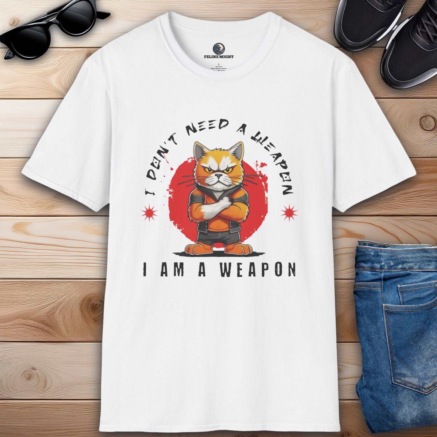 White t-shirt featuring a cartoon cat with the phrase 'I Don't Need A Weapon, I Am A Weapon'