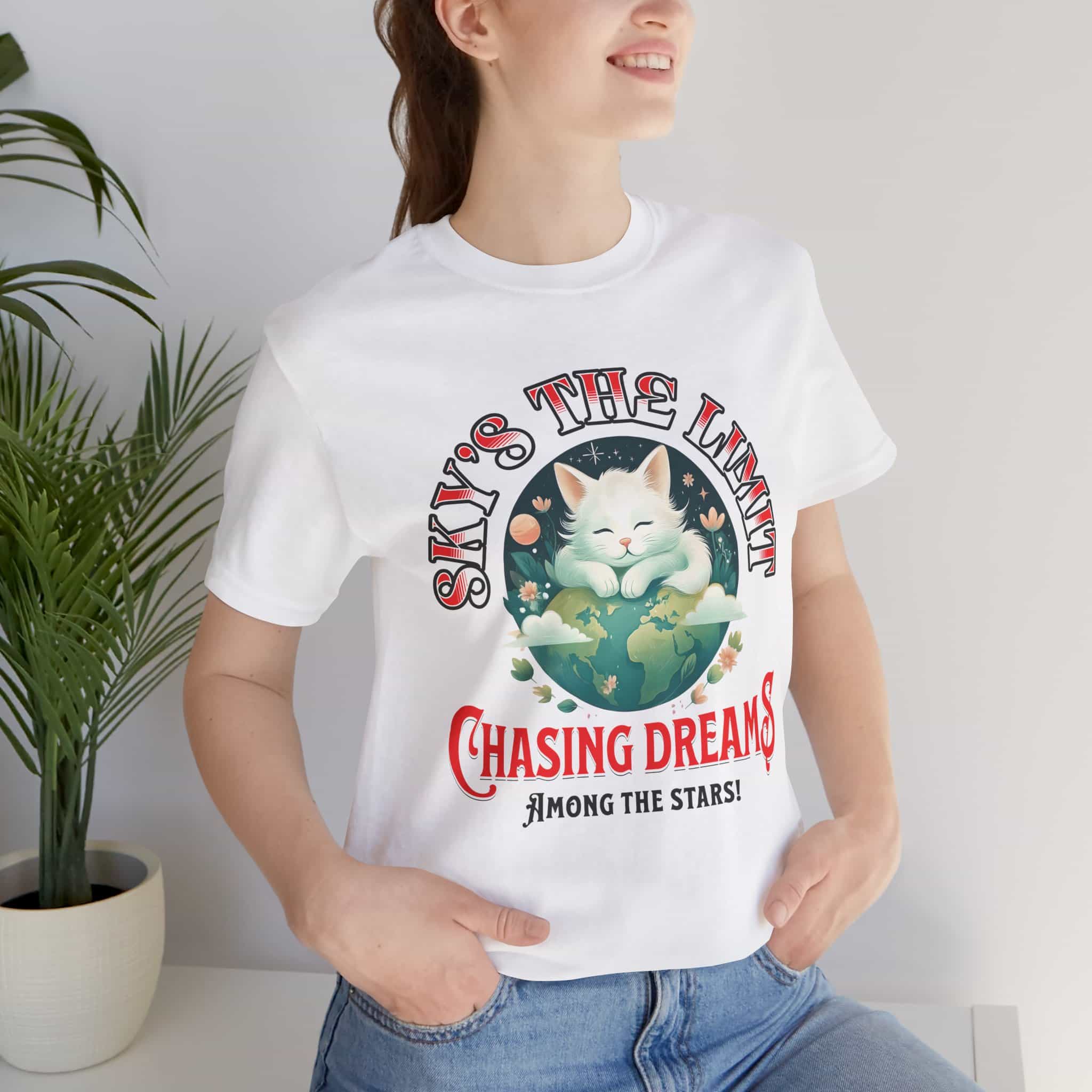 Woman wearing a white Sky's the Limit Cat T-Shirt featuring a motivational design with a cat and the phrase 'Sky's the Limit'.