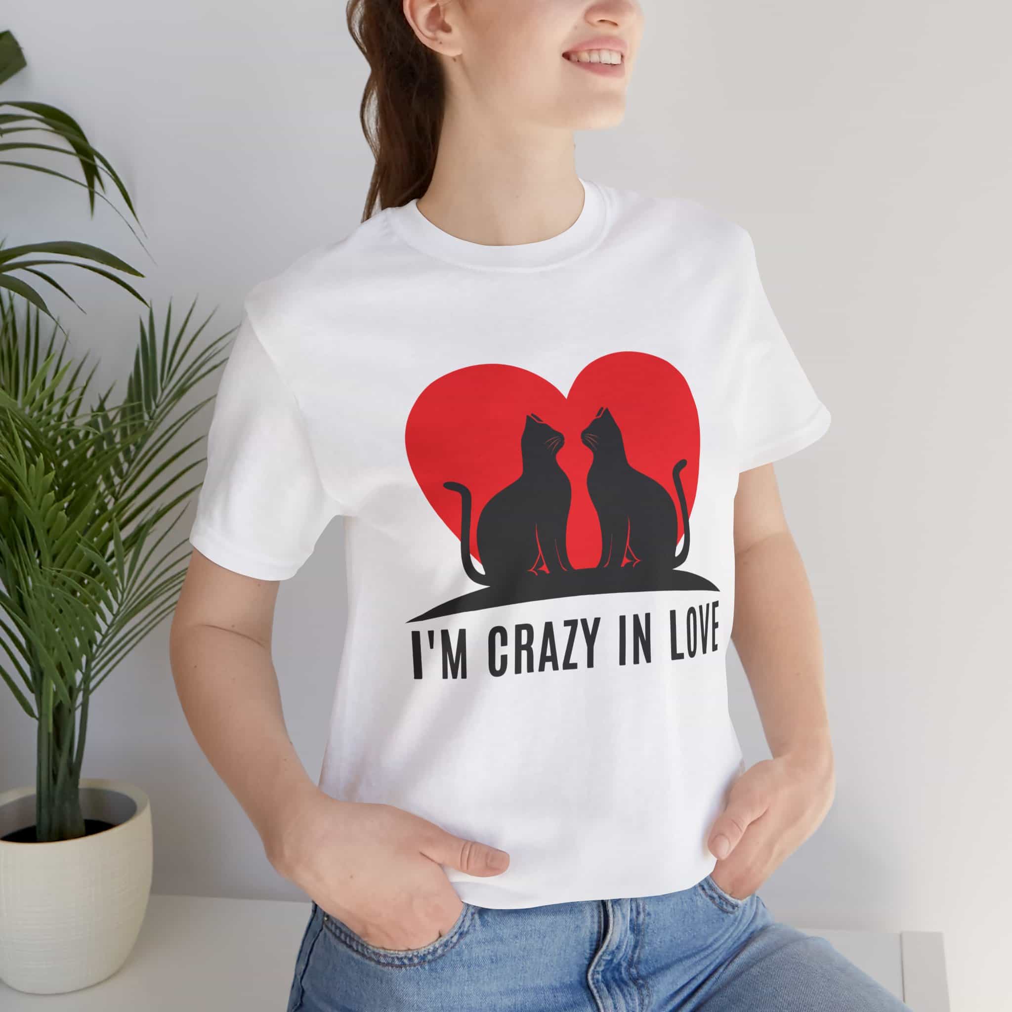 A woman in a white I'm Crazy in Love Cat T-Shirt featuring two cats with a heart design, perfect for romantic cat lovers.