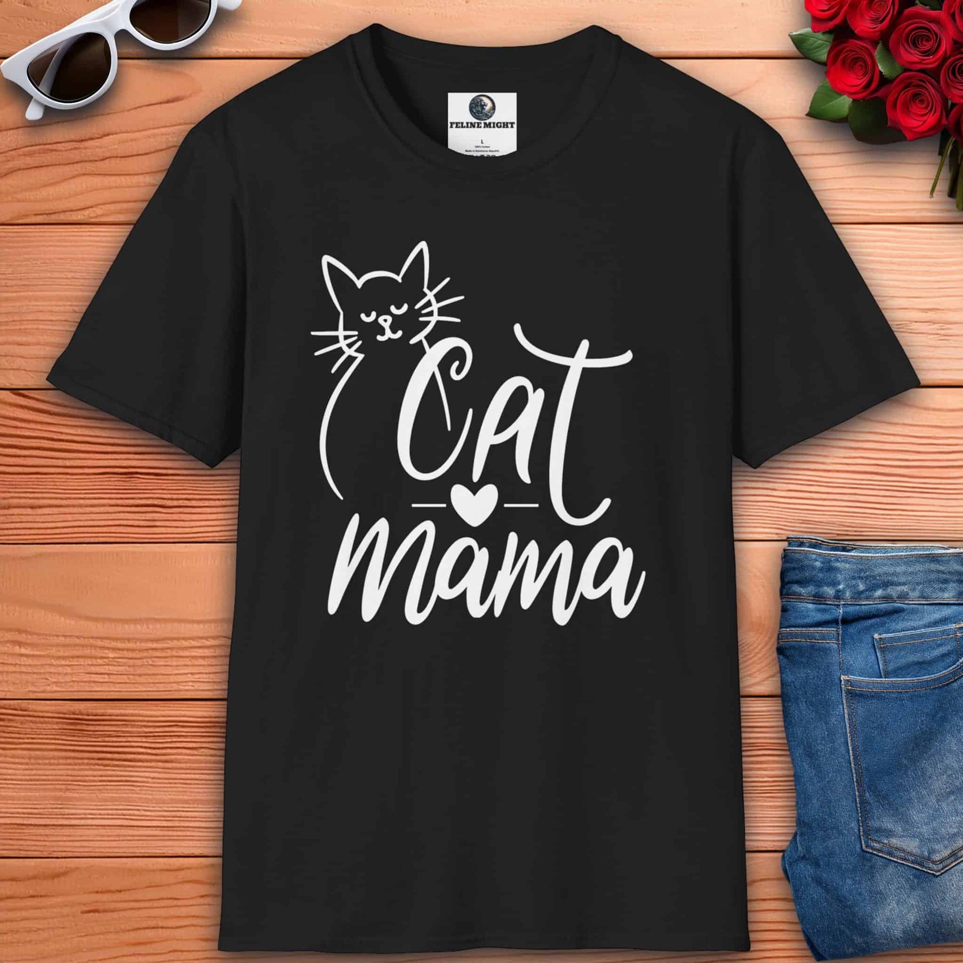 A black Cute Cat Mama T-shirt with 'Cat Mama' design on a wooden surface with sunglasses and flowers.