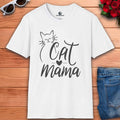 A white Sweet Cat Mama Graphic T-Shirt with 'Cat Mama' design on a wooden surface with sunglasses and flowers.