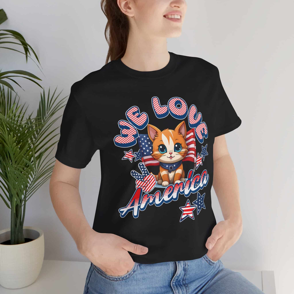 A woman in a black We Love America T-Shirt with a cheerful red, white, and blue cat design and the text “We Love America.”