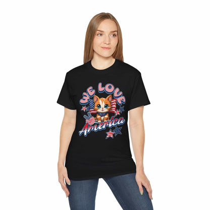A woman wearing a black Cute Patriotic Cat T-Shirt featuring a cheerful cat illustration in red, white, and blue with the text “We Love America.”