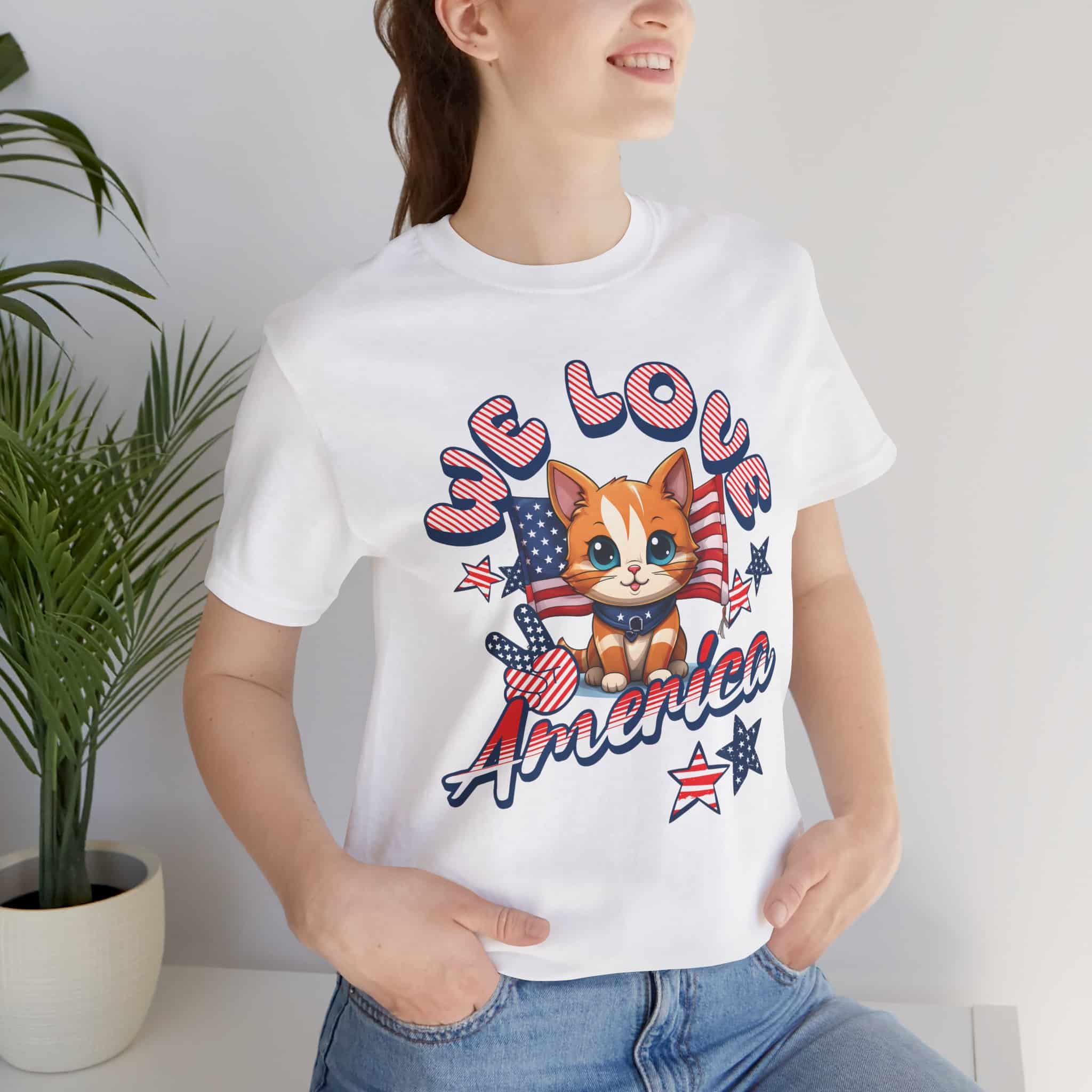 A woman in a white American Spirit Cat Graphic T-Shirt with a cheerful red, white, and blue cat design and the text “We Love America.”