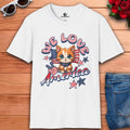 A white We Love America T-Shirt featuring a cat with stars and stripes, showing love for America.