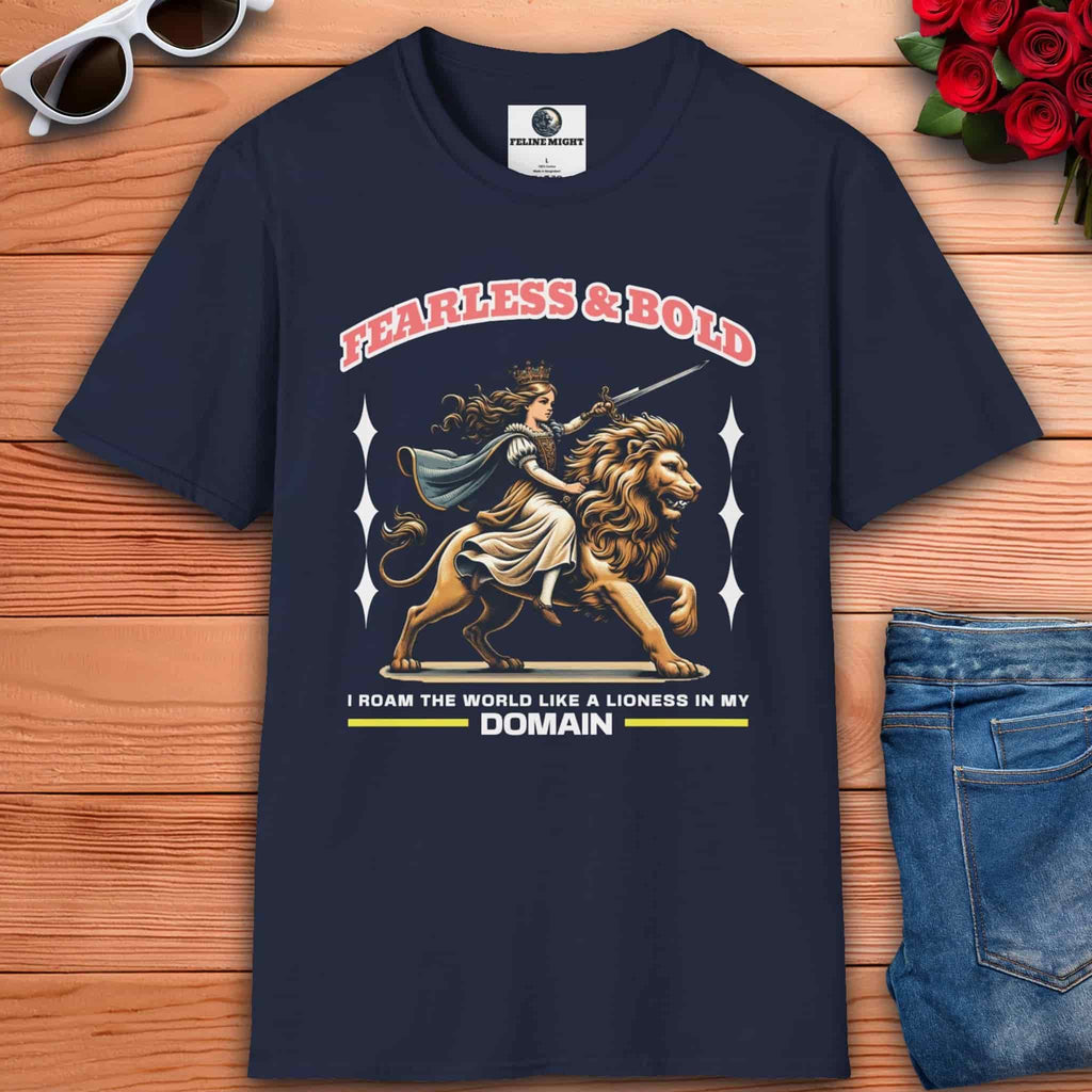 A navy blue Fearless Lioness Women's T-Shirt featuring a sword-wielding queen and lion design on a wooden surface with sunglasses and jeans.