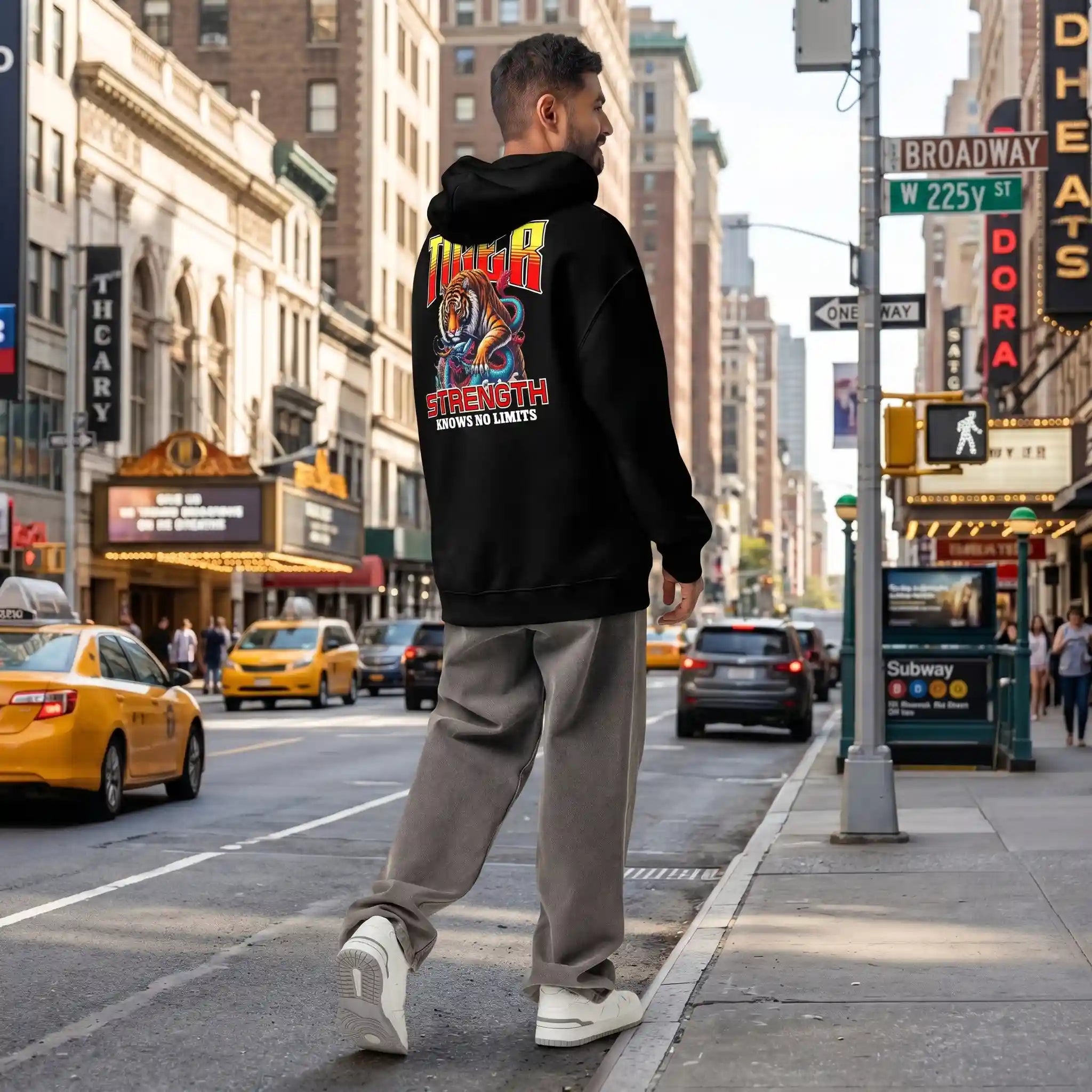 Mockup of a black hoodie from Feline Might with a tiger design on the back, worn by a man in a city street.