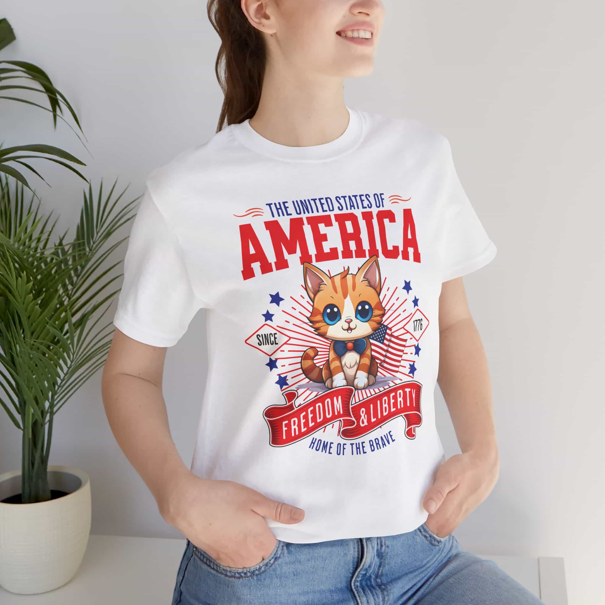 A woman wearing a white Liberty Cat Graphic T-Shirt featuring a cute kitten with American flag elements, perfect for patriotic cat lovers.