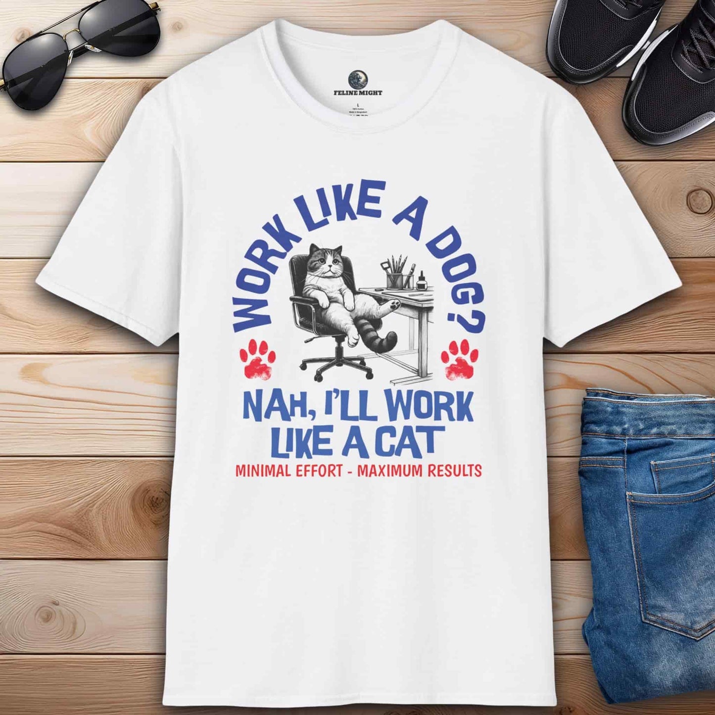 A white Funny Work Cat T-Shirt with a humorous cat graphic and the text 'Work like a dog? Nah, I'll work like a cat,' on a wooden surface with sunglasses and jeans.