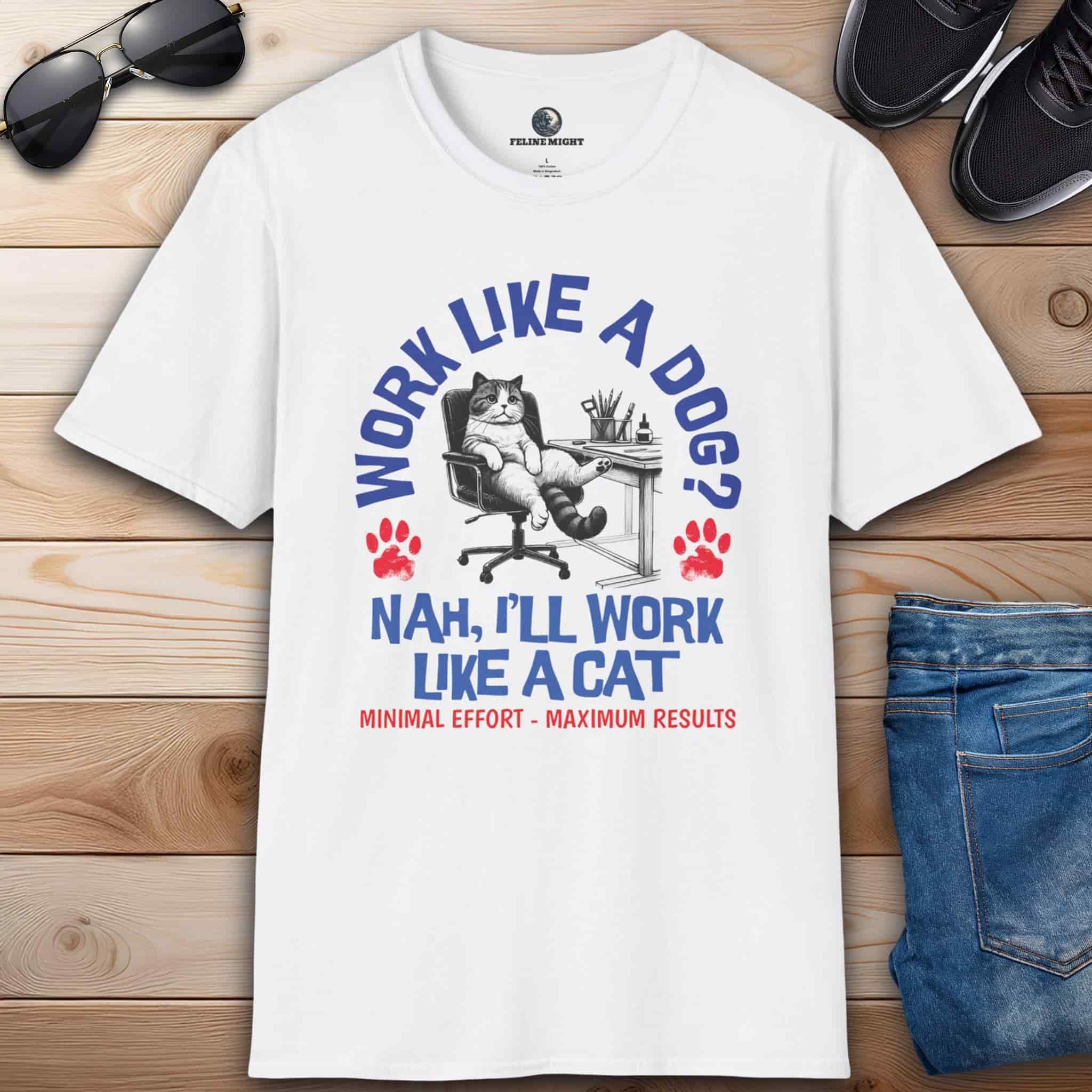 A white Funny Work Cat T-Shirt with a humorous cat graphic and the text 'Work like a dog? Nah, I'll work like a cat,' on a wooden surface with sunglasses and jeans.