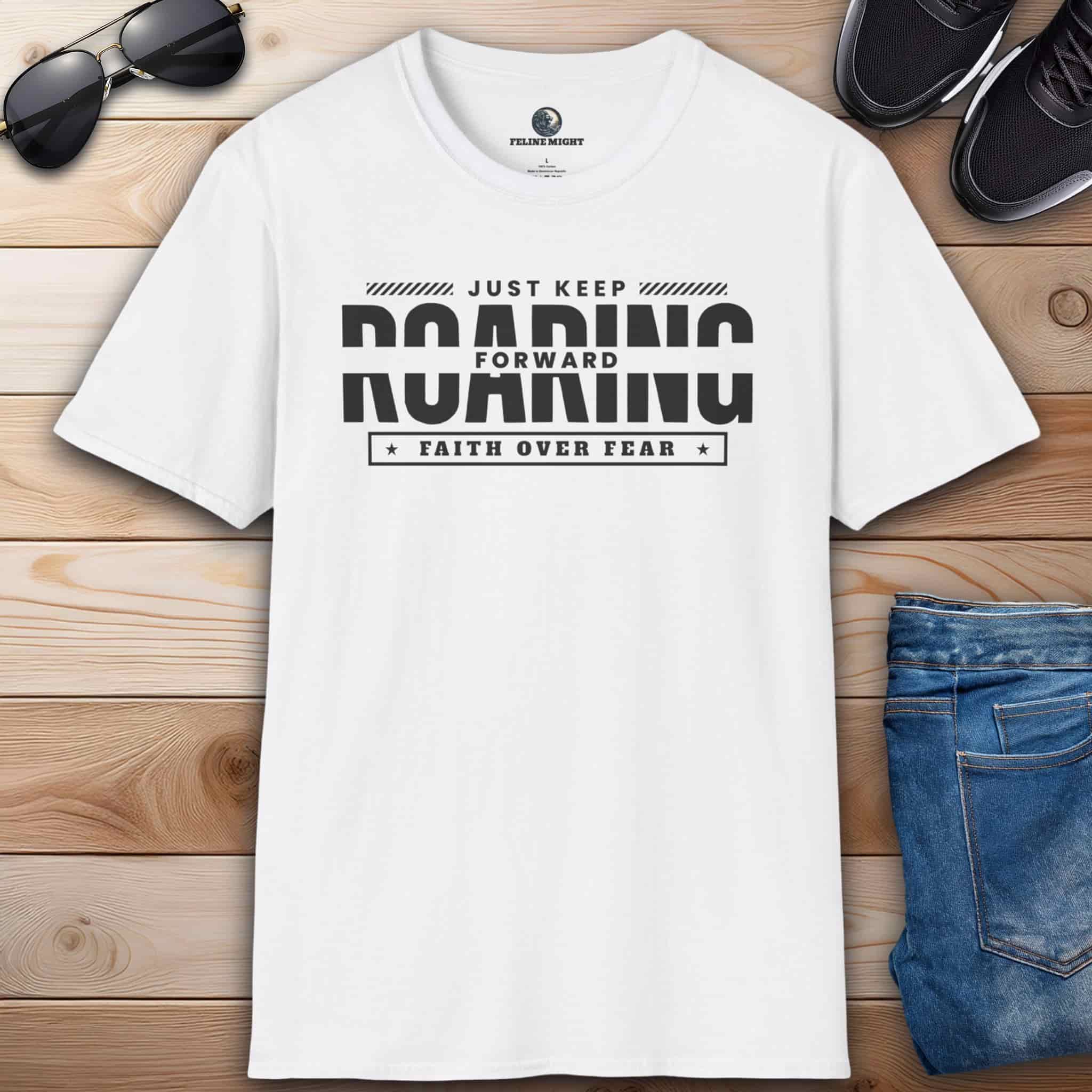 A white Just Keep Roaring Forward Quote Tee displayed on a wooden surface with sunglasses, sneakers, and jeans.