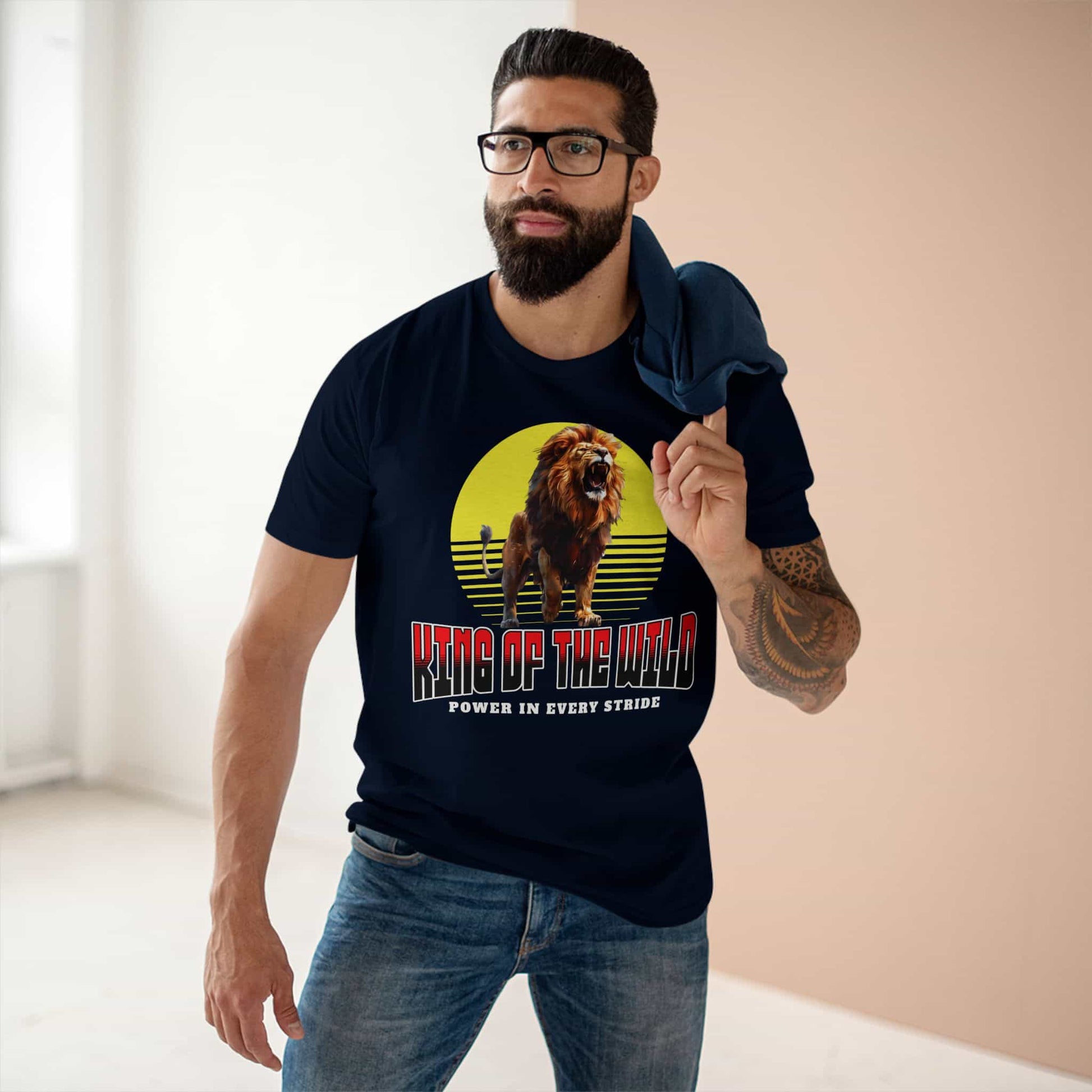 A man wearing a navy blue King of the Wild Lion T-Shirt featuring a bold lion graphic with the text 'Power in Every Stride'.