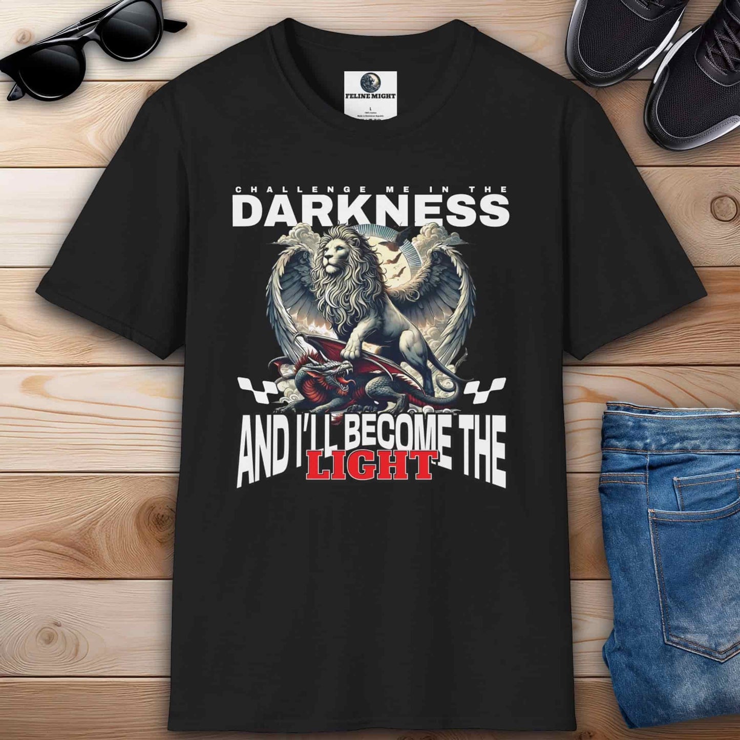 Black t-shirt featuring a lion graphic with the text 'Challenge me in the darkness and I'll become the light.'