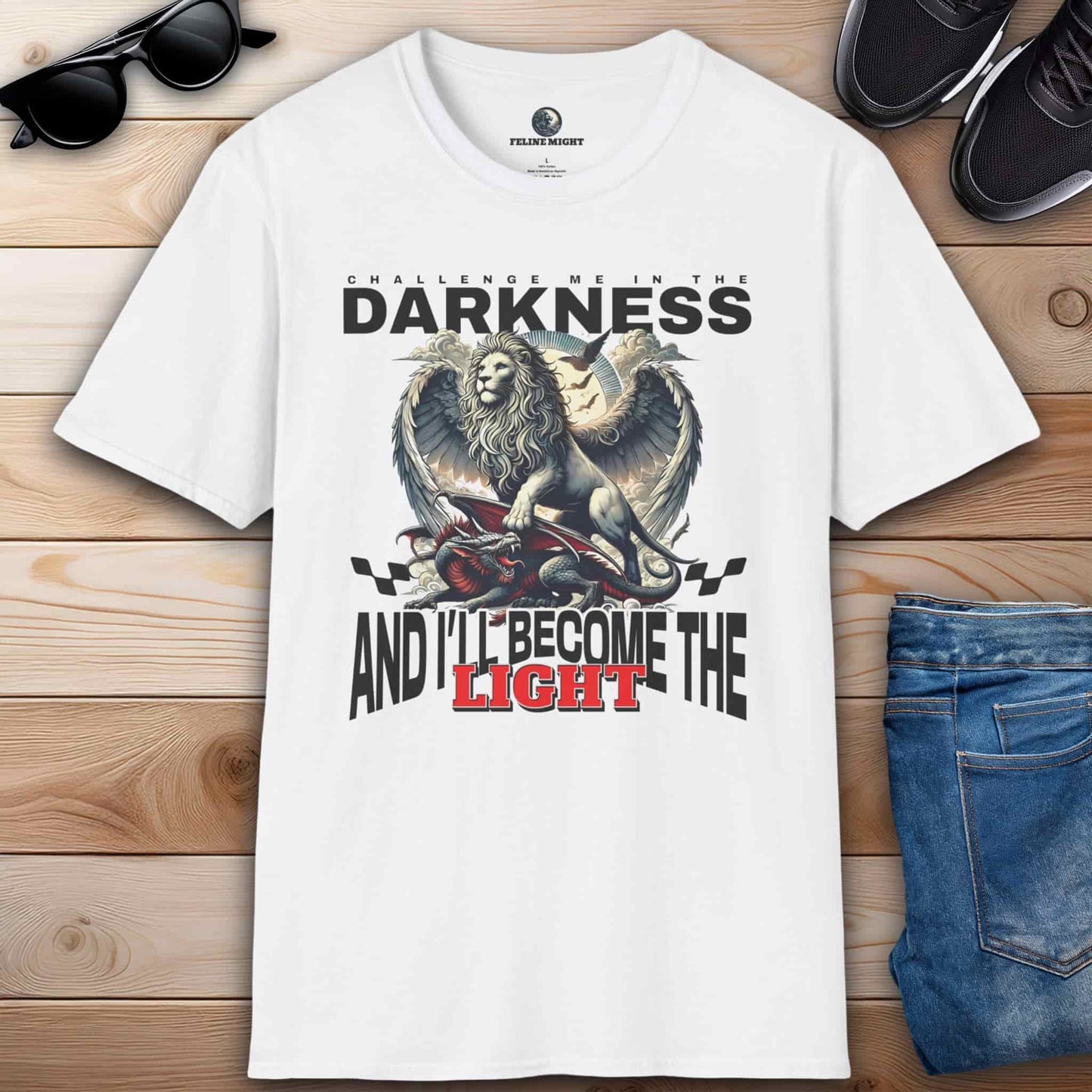 White t-shirt featuring a lion graphic with the text 'Challenge me in the darkness and I'll become the light.'