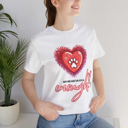 A person wearing a white My Heart is Full Cat T-shirt with a heart and paw print design, standing indoors next to a plant.