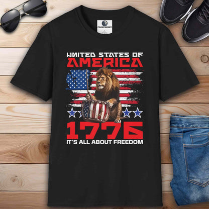 A black Patriotic Lion Freedom T-Shirt featuring a drum-playing lion and the American flag with text '1776 It's All About Freedom'.