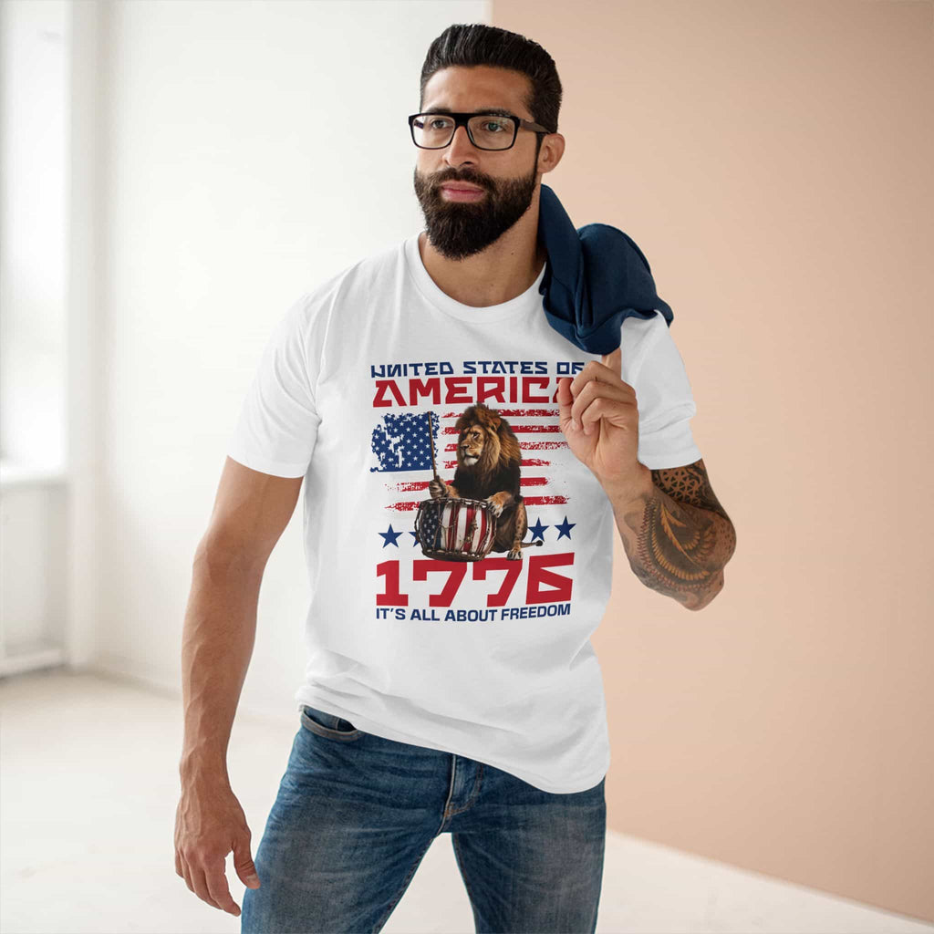 A man wearing a white It's All About Freedom T-Shirt, featuring a drum-playing lion, the American flag, and the text 'It's All About Freedom'.
