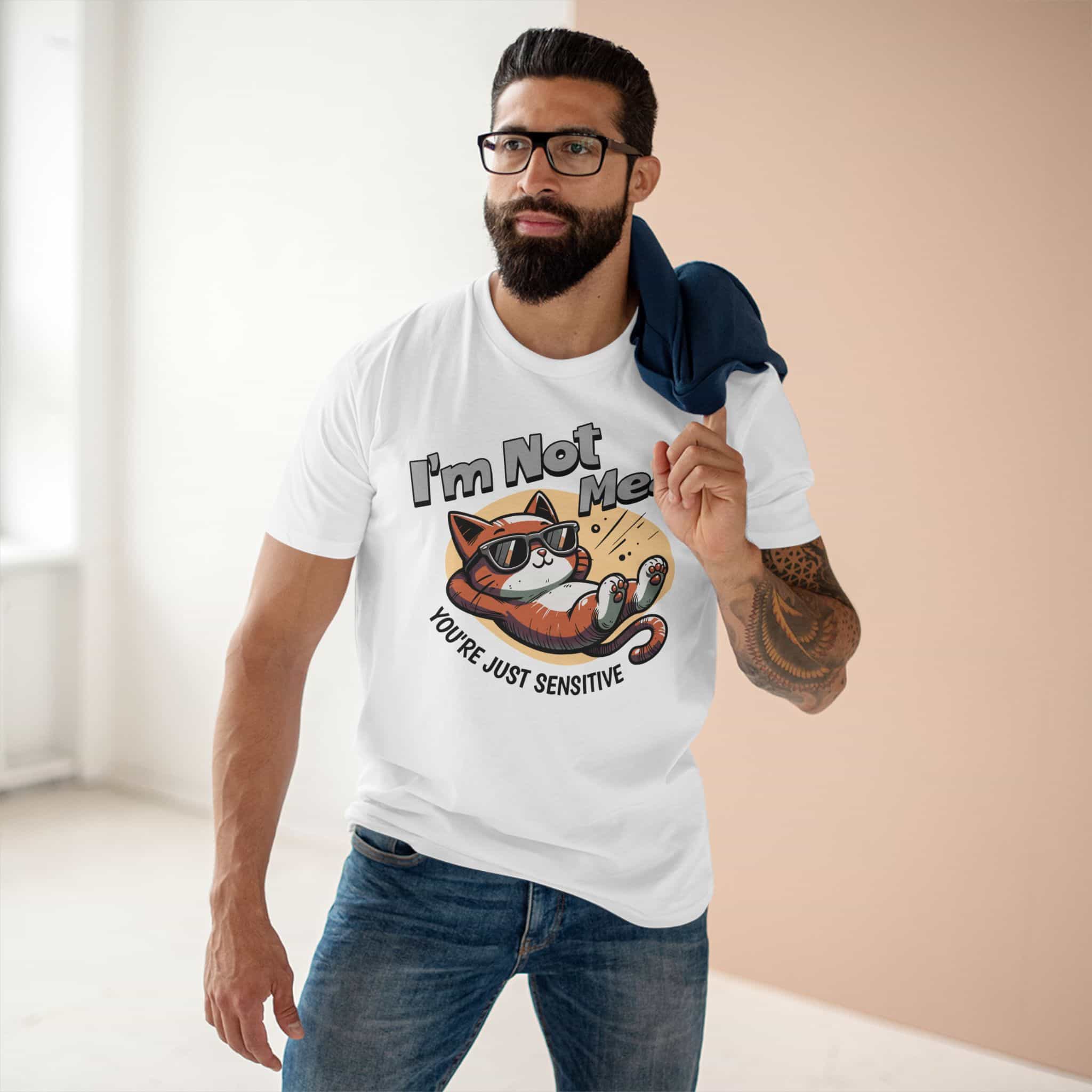 A man wearing a white Sarcastic Cat Humor T-Shirt with a graphic of a cat wearing sunglasses and the text 'I'm Not Mean, You're Just Sensitive'.