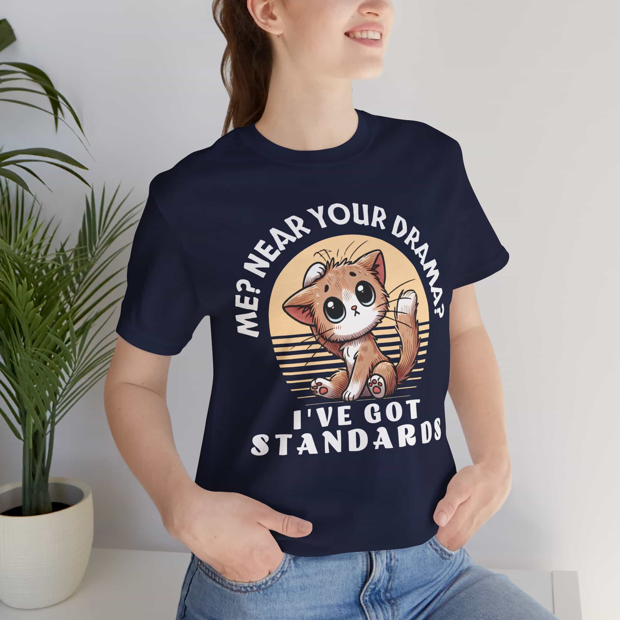 A woman wearing a navy blue Sassy Cat Graphic T-Shirt featuring a humorous design with a cute cat and text saying 'Me? Near Your Drama? I've Got Standards.'