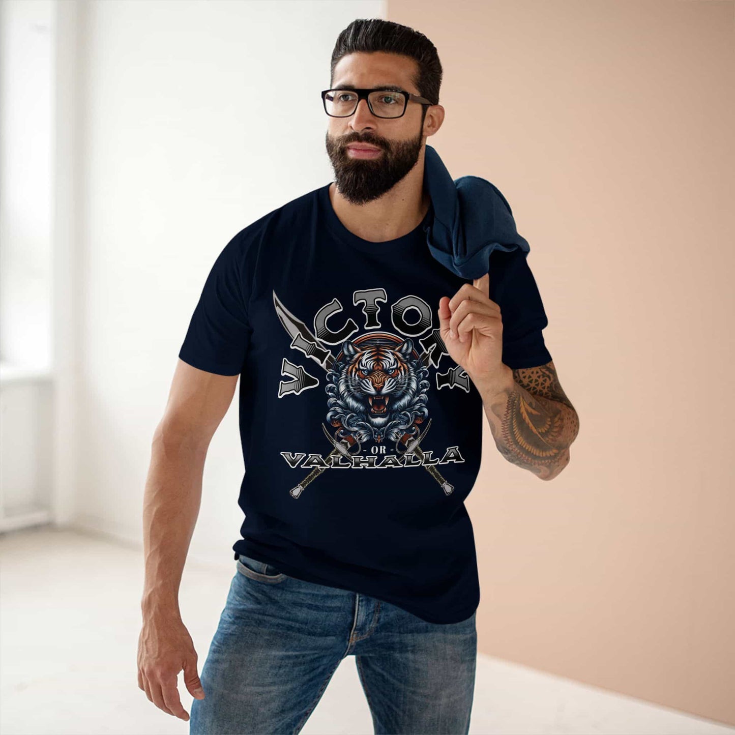 A man wearing a navy blue Victory or Valhalla Tiger T-Shirt featuring bold design with tiger and crossed swords.