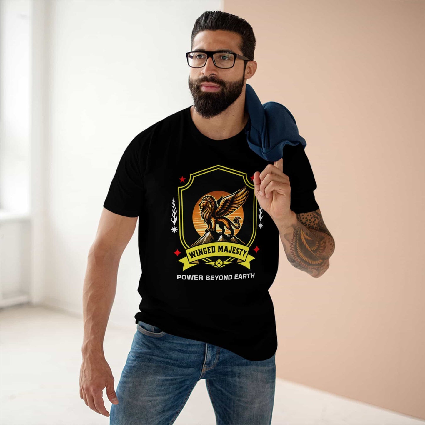 A man wearing a black Winged Majesty Lion T-Shirt featuring a golden-winged lion graphic and the text 'Power Beyond Earth', standing indoors.